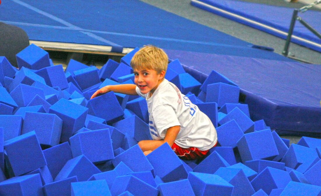 A young gymnast playing in the foam pit